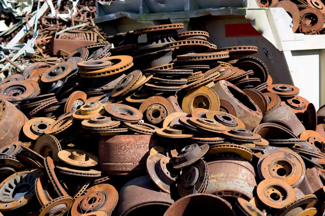 A large pile of rusted metal brake discs and automotive parts stacked in a scrap yard.