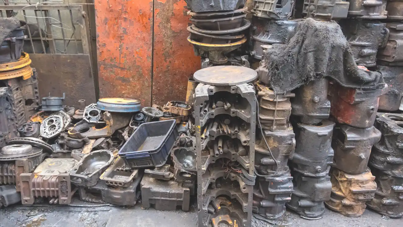 Stacks of used gearbox housings, engine blocks, and automotive parts arranged in a secondhand parts market.