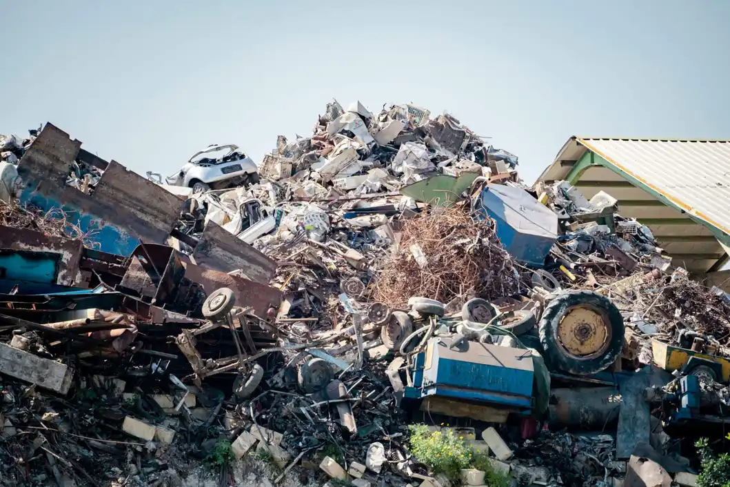 A towering heap of crushed and rusted scrap metal, including demolished vehicles, at a company.