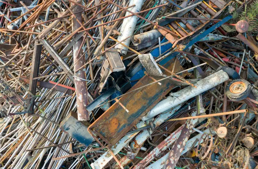 Aerial view of a dense pile of rusted metal rods, pipes, and old machinery parts at a scrapyard.