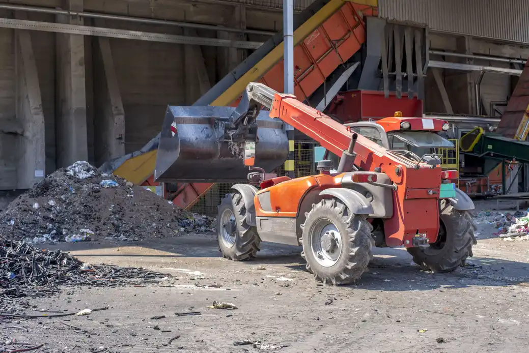 Loader transporting bulk waste materials at treatment plant
